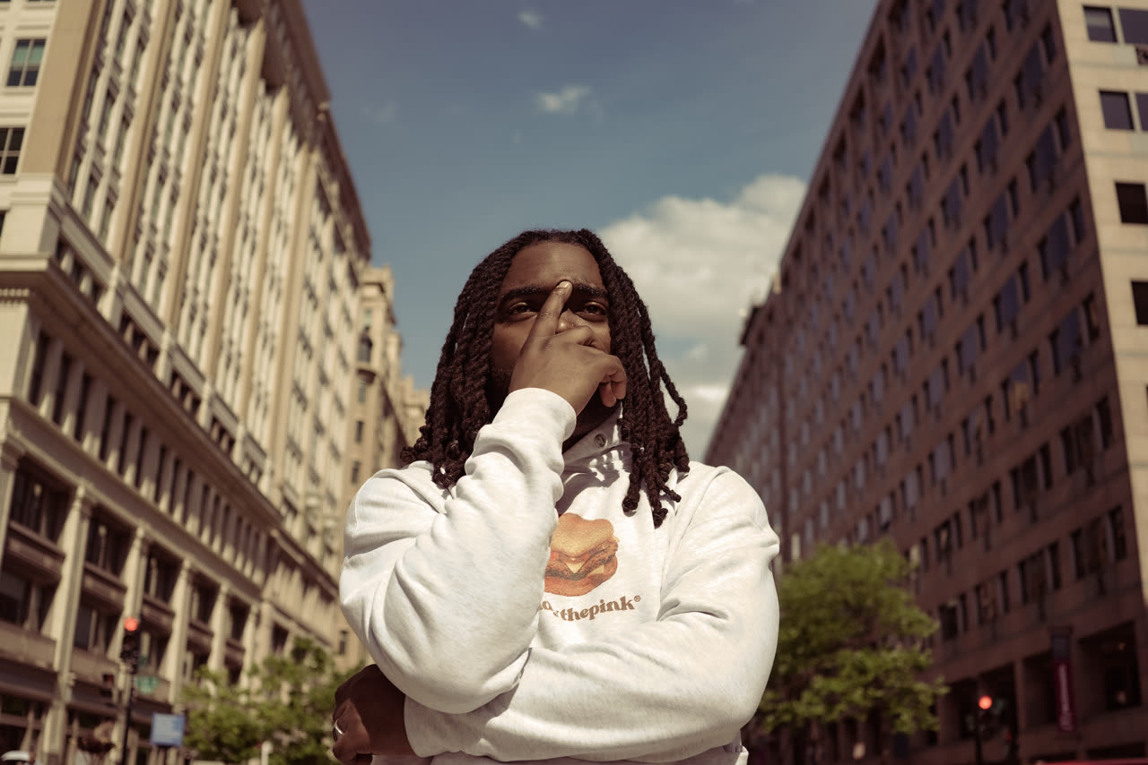 Go Ezko standing on a downtown Washington D.C. street, buildings rising on both sides.